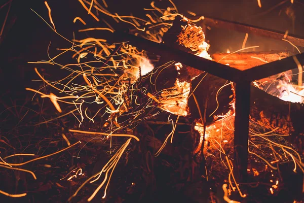 Vonken van een brand vliegen in verschillende richtingen in de nacht — Stockfoto