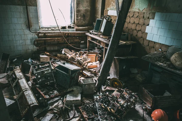 Raum mit altem Müll in verlassener Fabrik, Bauhelme liegen auf dem Boden, Industriemüll — Stockfoto