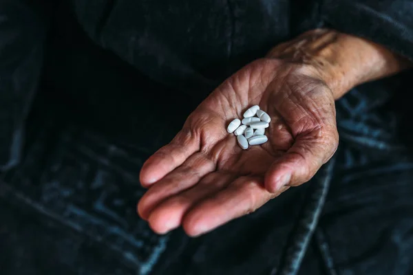 Χούφτα λευκά δισκία ή χάπια στα χέρια του μια ηλικιωμένη γυναίκα — Φωτογραφία Αρχείου
