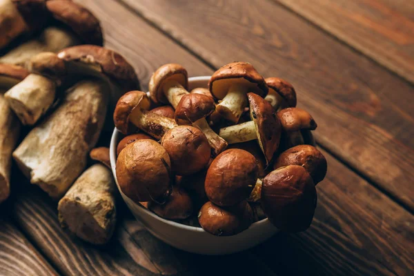 Paddestoelen in plaat en op houten keukentafel — Stockfoto