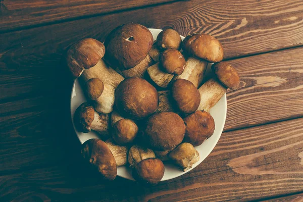 Tampilan atas piring dengan jamur porcini di atas meja kayu pedesaan — Stok Foto