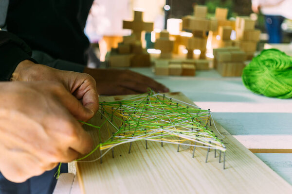 Close-up of male hands making a picture of threads and nails