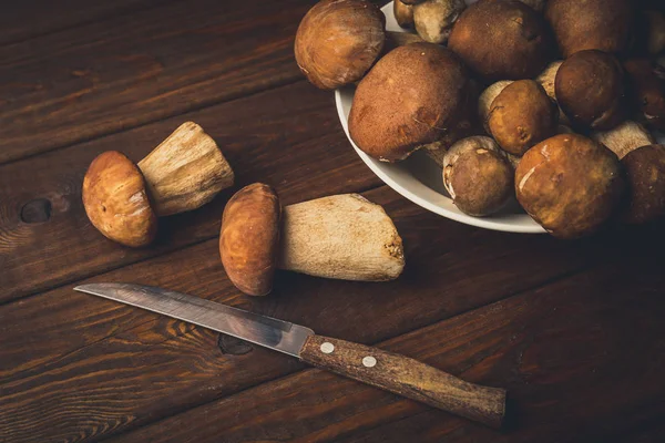Porcini paddestoelen op houten tafel in plaat en mes voor het koken — Stockfoto