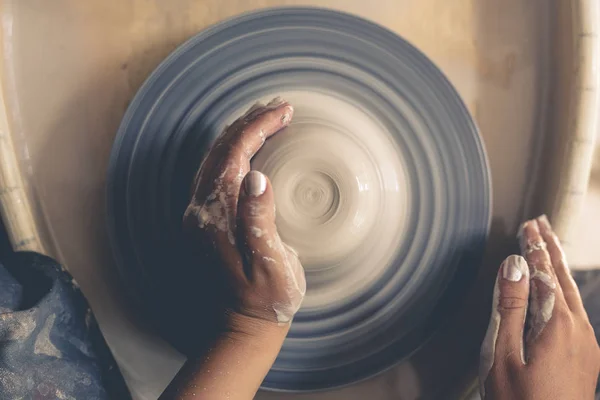 Руки женщины гончара работают на гончарном круге, вид сверху — стоковое фото