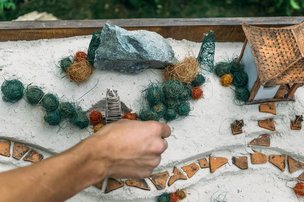 Miniature houses, toy landscape objects on the sand. Anti-stress and soothing sand therapy