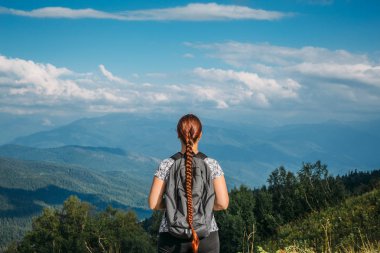 Kadın uzun yürüyüşe çıkan kimse sırt çantası ile dağın tepesinde duruyor ve vadi, dağ manzarası görünüyor