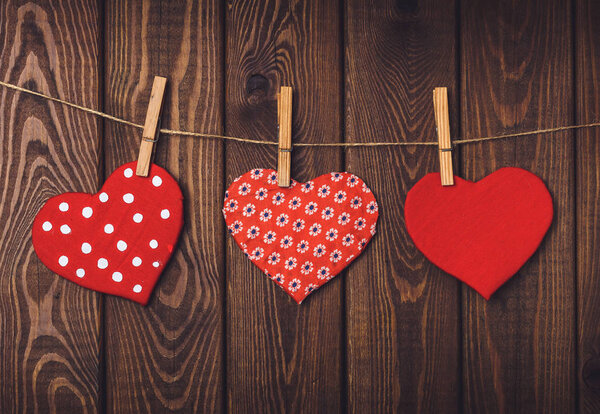 handmade toy hearts hanging from a rope on a dark wooden background. Valentine 