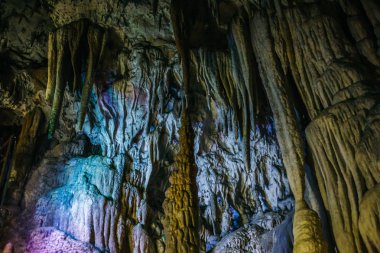 Beautiful illuminated limestone stalactites in Adygeya underground cave, speleology grotto clipart