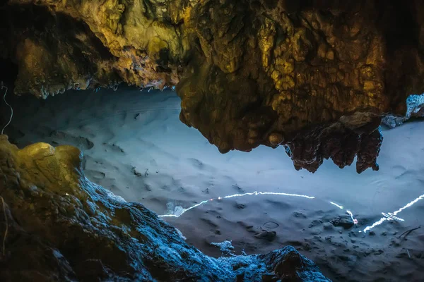 Hermosas estalactitas de piedra caliza iluminada en la cueva de Adygeya, río subterráneo con reflejo de luz azul —  Fotos de Stock