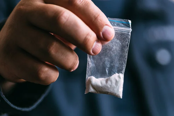 Έμπορος ναρκωτικών πώλησης ναρκωτικών πρεζόνι. Έννοια κατάχρηση ναρκωτικών και υπερδοσολογία έννοια. Επανδρώνει το χέρι κρατά το πλαστικό πακέτο με κοκαΐνης σε σκόνη — Φωτογραφία Αρχείου