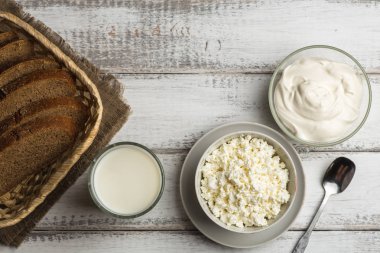 Mandıra gıda: top kopya alanı görünümüyle lor peynir ve kaseler, süt ve taze ekmek sepeti rustik arka plan üzerinde krem