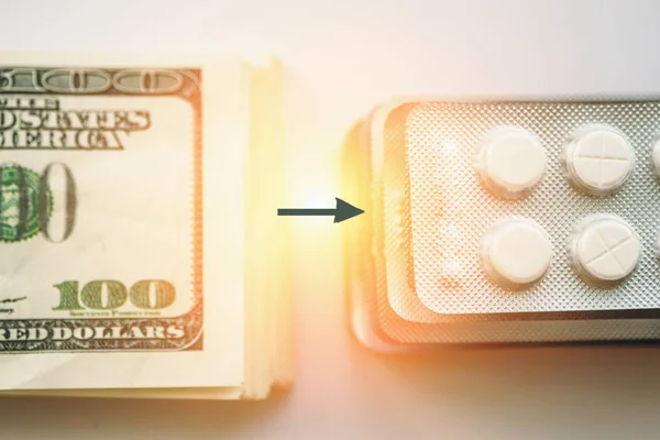 Δέσμη των χρημάτων και βέλος pack των δισκίων φαρμακευτική αγωγή ή ναρκωτικά χάπια, γκρο πλαν. Ακριβά υγειονομική περίθαλψη ή τα χρήματα είναι υγεία έννοια, επιλεκτική εστίαση — Φωτογραφία Αρχείου