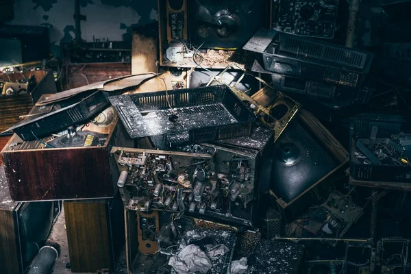 Sekelompok televisi antik tua atau kotak TV rusak dalam gelap menyeramkan rumah di antara sampah di ruang kotor — Stok Foto