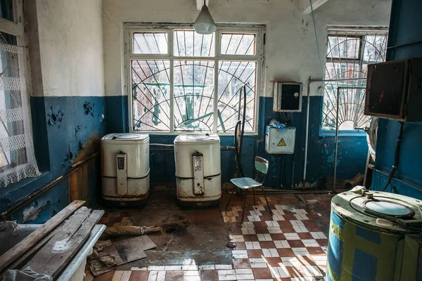 Abandoned laundry building, old washing machines, rusty baths