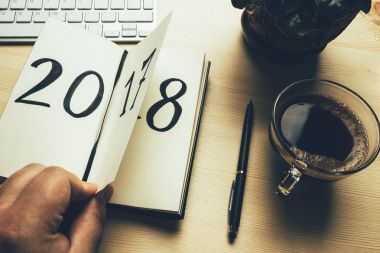 Yeni yıl 2018 önümüzdeki kavramdır. El ahşap masa üzerinde Not Defteri sayfası döndürür. 2017 dönüyor, 2018 açma