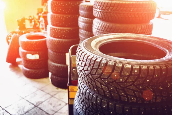 Novos pneus de inverno em pilhas dentro do serviço de garagem automotiva - mudança de rodas ou pneus — Fotografia de Stock