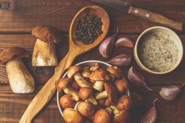 Ahşap rustik masa veya kesme tahtası, baharat, sarımsak ve otlar tahta kaşıkla Porcini veya beyaz ham mantar