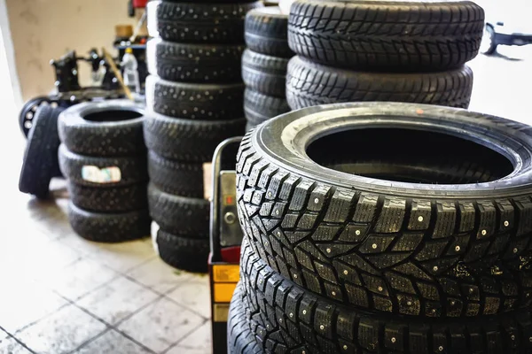 New winter tires in stacks inside automotive garage service - changing wheels or tires — Stock Photo, Image