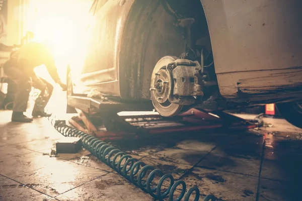 O mecânico do carro substitui as rodas do carro do automóvel levantado pela chave pneumática na estação da garagem da oficina do serviço de reparação, efeito da luz solar — Fotografia de Stock