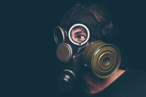 Pós homem sobrevivente apocalíptico em máscara de gás em fundo preto, olhos assustadores — Fotografia de Stock