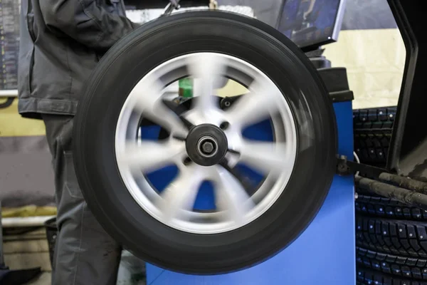 Process of balancing and fitting car tire wheel in motion, auto repair service, garage — Stock Photo, Image