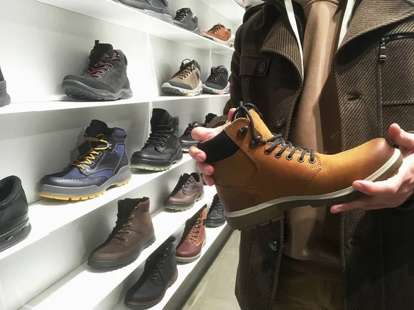 Jonge man kopen of kies winter schoenen in schoenenwinkel — Stockfoto