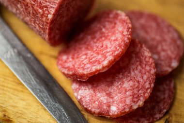 Salam bıçak, makro fotoğraf ile ahşap kesme tahtası üzerinde. Sosis, üstten görünüm, dilim yakın çekim