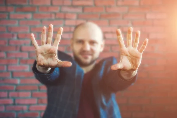 Unga hypnotisör eller affärsman i en jacka leende och visar händer utsträckta framåt med handflatorna — Stockfoto