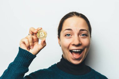 Genç gülümseyen kız altın Bitcoin gösterir mutlu el - cryptocurrency, yeni sanal para sembol sikke