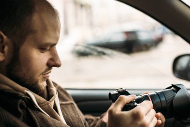 Araştırmacı veya özel dedektif veya muhabir veya araba ve çekici fotoğraf profesyonel fotoğraf makinesi ile oturma paparazzi