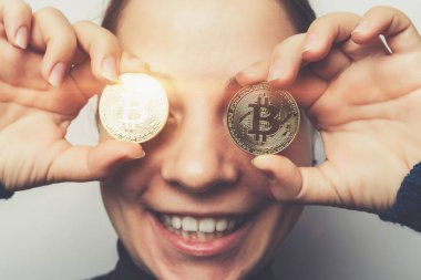Genç gülümseyen kız altın Bitcoin tutan mutlu elinde önünde gözleri - cryptocurrency, yeni sanal para sembol sikke