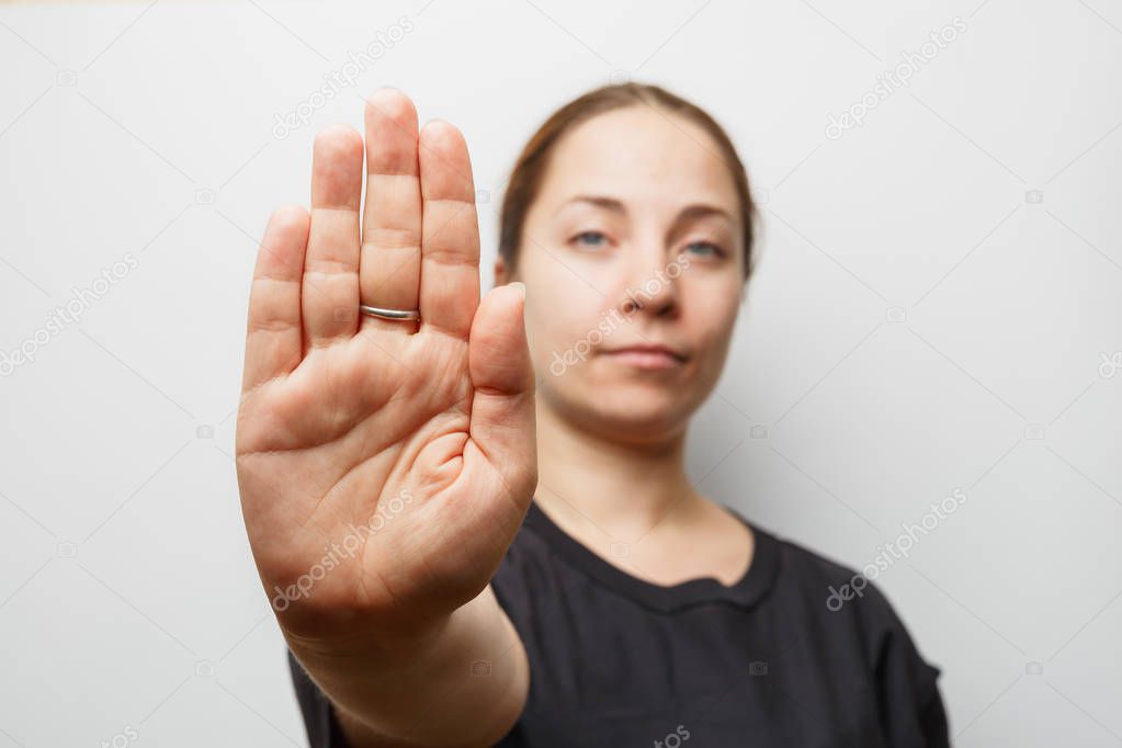 Girl showing STOP sign or NO gesture by hand, focus on palm