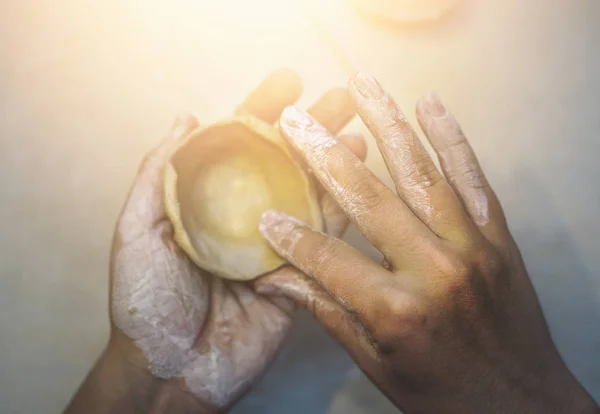 O oleiro feminino trabalha com argila, mãos de artesão. Vista superior da forma de moldagem para tigela de argila por dedos, efeito de luz — Fotografia de Stock