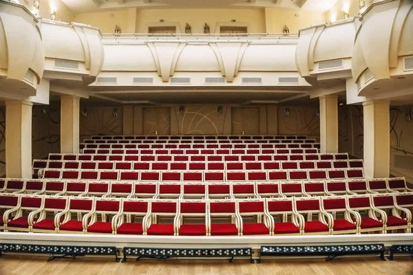 Belgorod, Rusia - CIRCA enero 2018: Interior de salón enorme vacío con filas de sillas rojas y columnas de edificio filarmónico — Foto de Stock