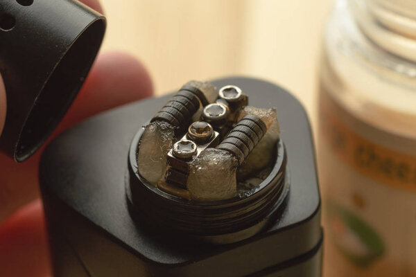 Rebuildable dripping atomizer or RDA for vaping or e-cigarette with coil and cotton stripes wetted with e-liquid, modern vape device for quit smoking