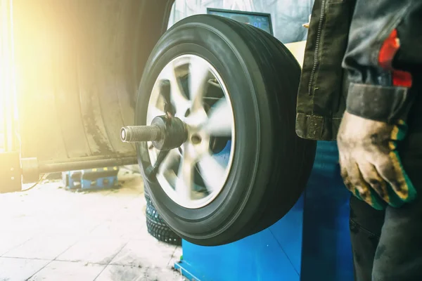 Balanceamento de rodas ou reparação e mudança de pneu de carro na garagem ou oficina de serviço de automóvel por mecânico — Fotografia de Stock