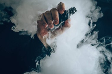 Adam el buharı arka plan bulut vape aygıtı gösterir. Vape kavramı