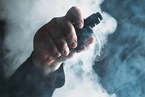 Man hand shows vape device at cloud of vapor background. Vape concept — Stock Photo, Image