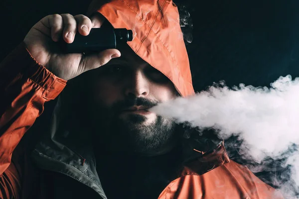 Homem fumante vaping e-cigarro com e-líquido de vape dispositivo RDA, respira vapor e olha para a câmera. Conceito de violação — Fotografia de Stock