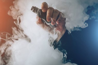 Adam el buharı arka plan bulut vape aygıtı gösterir. Vape kavramı