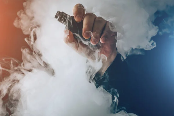 Man hand shows vape device at cloud of vapor background. Vape concept — Stock Photo, Image