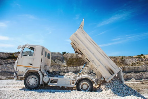 Карьерный грузовик выгружает белый известняковый гравий в каменоломню — стоковое фото