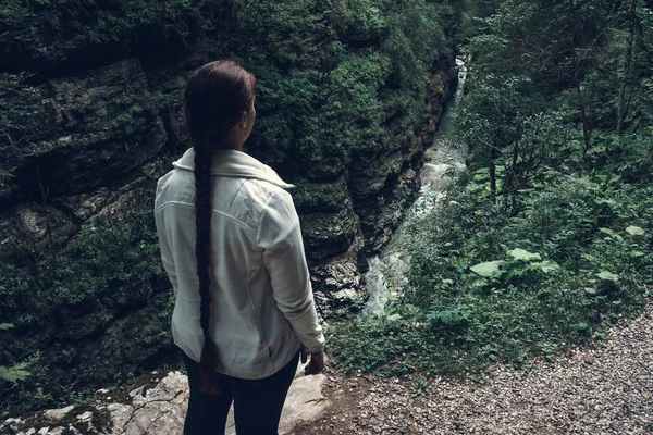 Unga resande kvinna promenader tittar på mountain river i canyon. Resa äventyr och vandring aktivitet koncept — Stockfoto