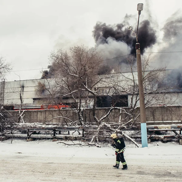 Pompier allant à gauche à brûler bâtiment industriel avec des flammes de feu et fond de fumée noire — Photo