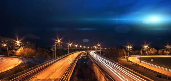 Bright blue light UFO ship fly above city and blurred road traffic at night — Stock Photo, Image