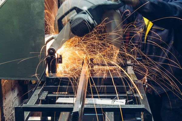 Elektrische circulaire grinder in metaalbewerking fabriek. Werknemer snijdt metaal, close-up. Sparks tijdens het slijpen van staal of ijzer delen — Stockfoto