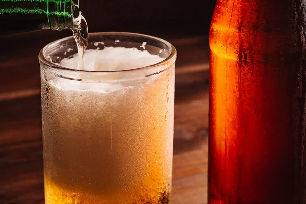 Despejar cerveja espumante em caneca de vidro com gotas perto de bebida de cerveja gelada — Fotografia de Stock