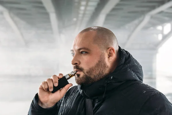 Vape-manden. Ung fyr vaping elektronisk cigaret eller vape pen på urban baggrund, moderne livsstil - Stock-foto