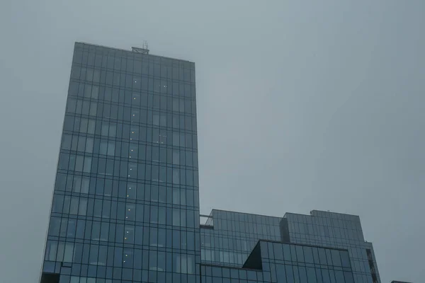 Torre del moderno edificio de cristal rascacielos en niebla o niebla — Foto de Stock