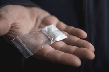 Palmiye Plastik paket kokain toz veya başka bir ilaç ile üzerinde tutan el mans. Narkotik konsept denemek uyuşturucu satıcısı öneriyor